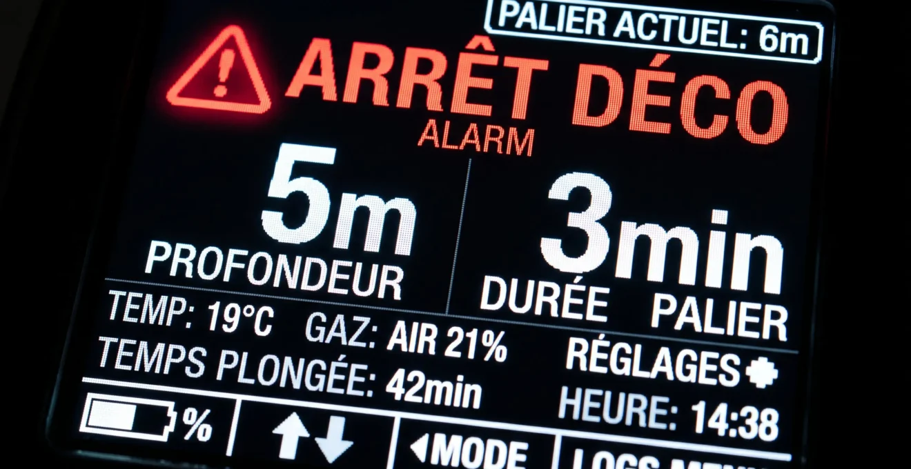 Écran d'ordinateur de plongée affichant une alarme de palier de décompression avec indication 'ARRÊT DÉCO', profondeur 5m et durée 3min en grands caractères rétroéclairés
